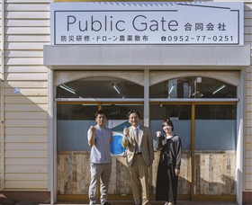 会社前で集合写真に映る公門さんたちと知事