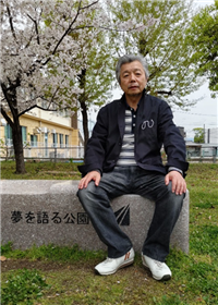 『夢を語る公園』と刻まれたベンチに腰掛ける福島さん