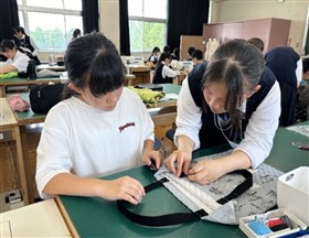 小学生にミシンの使い方を指導している様子